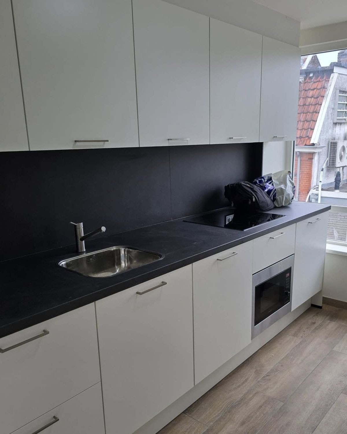 Gemonteerde witte keuken met zwart werkblad en spoelbak