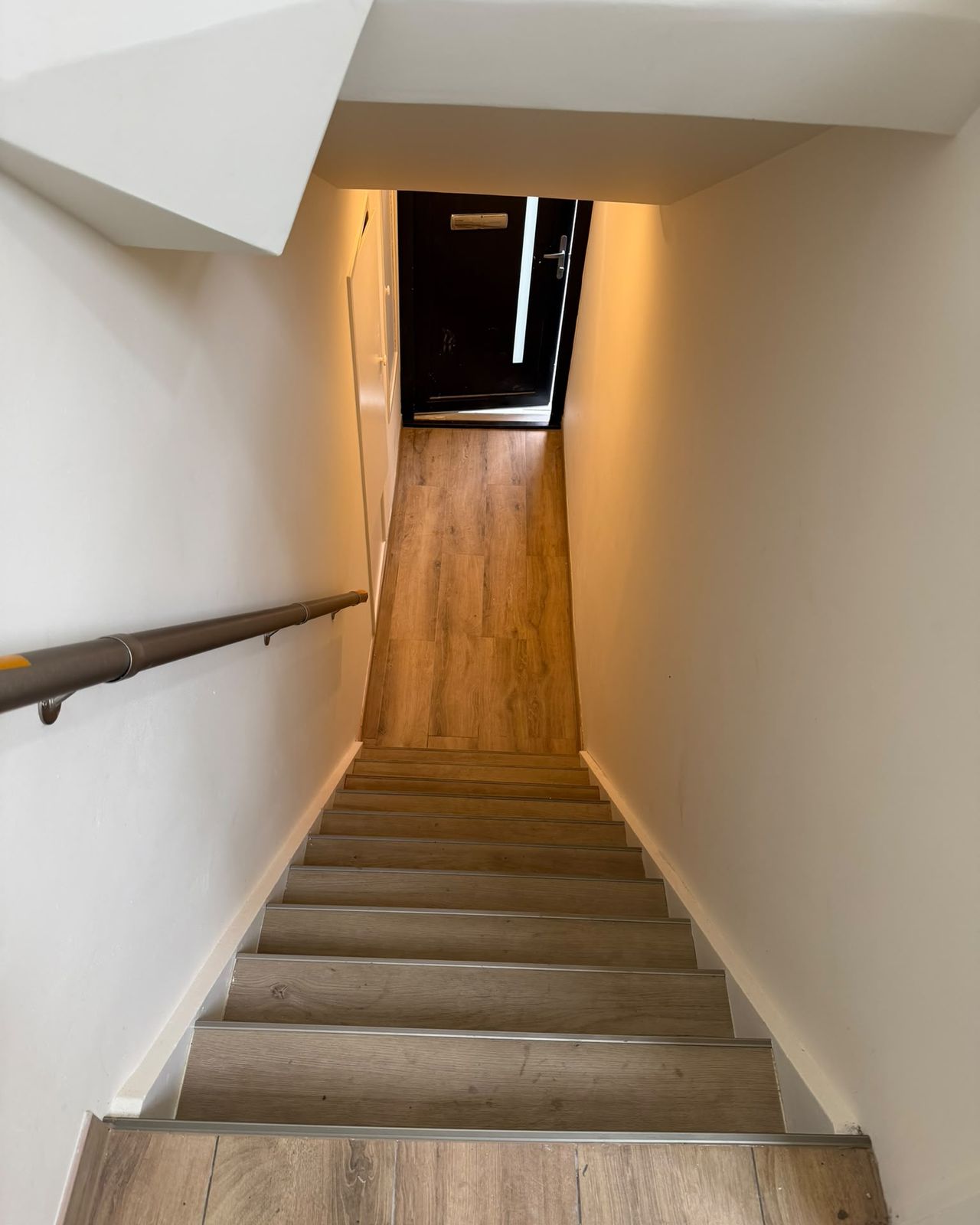 Trap met houtlook treden en strak afgewerkte witte wanden