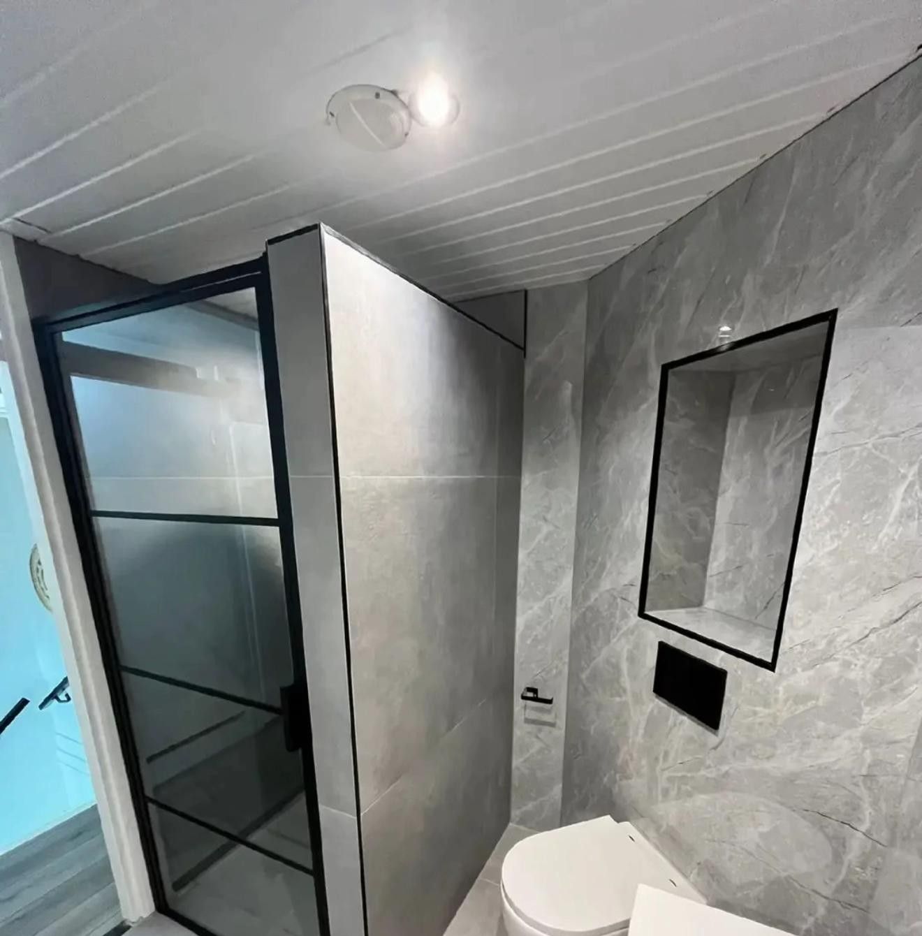 Inloopdouche met zwart kader en hangend toilet in grijze marmerlook