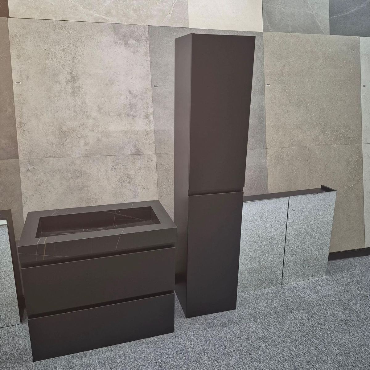 Donker wastafelmeubel en hoge kast voor grote tegels in de showroom
