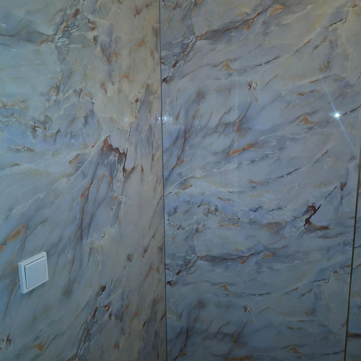 Wand van grote tegels in blauwgrijze marmerlook