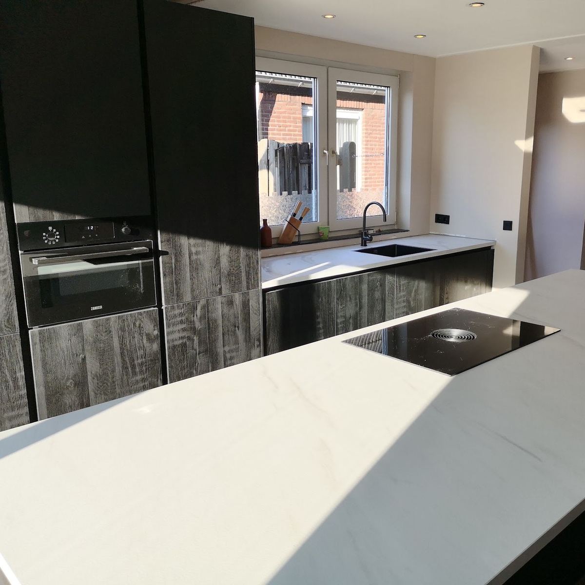 Keuken met wit kookeiland en kasten in houtlook