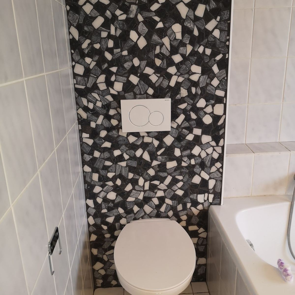 Hangend toilet voor een wand van zwart-wit mozaïek